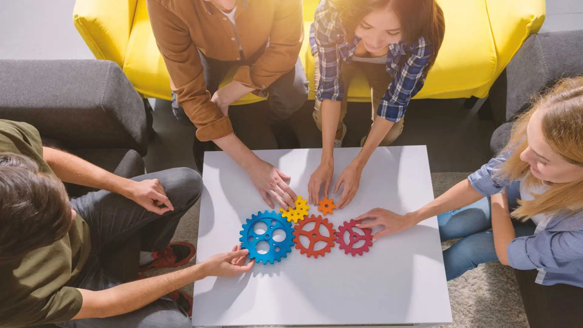 Trabalhadores montam engrenagens coloridas durante avaliação de competências técnicas e comportamentais.